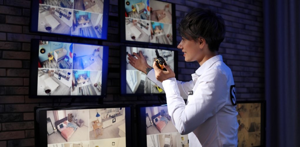 Female,Security,Guard,With,Portable,Transmitter,Monitoring,Home,Cameras,Indoors